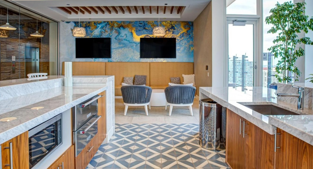 Stylish resident lounge with a modern kitchen island, comfortable seating areas, and a vibrant accent wall at Eleven40 apartments in Chicago