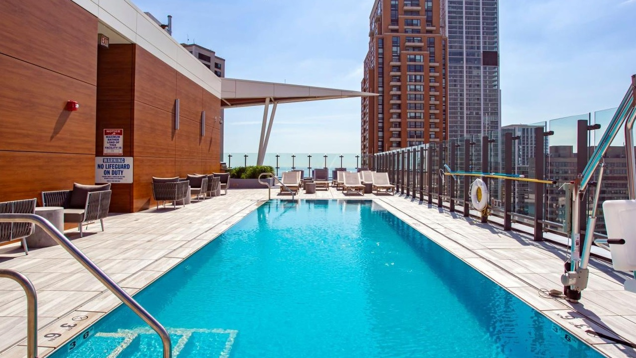 Sparkling rooftop swimming pool surrounded by lounge chairs, offering panoramic city views at Eleven40 apartments in Chicago