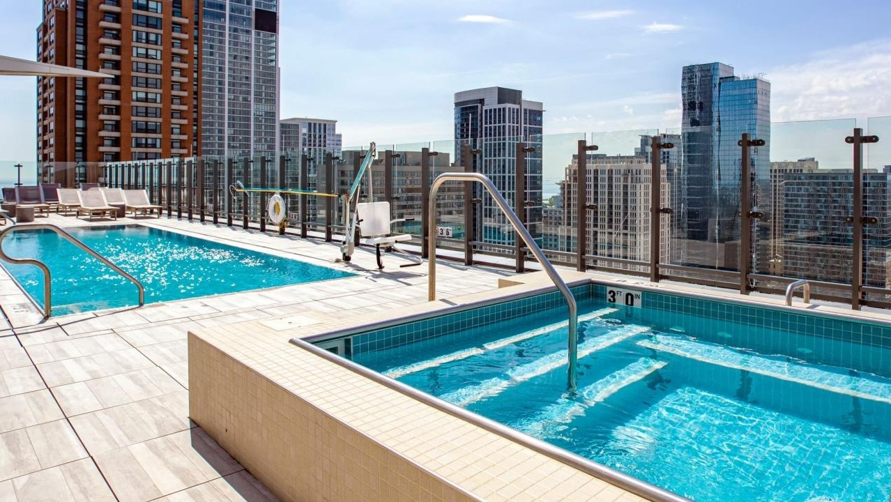 Luxurious rooftop pool and hot tub area with stunning city skyline views, perfect for relaxation at Eleven40 apartments in Chicago