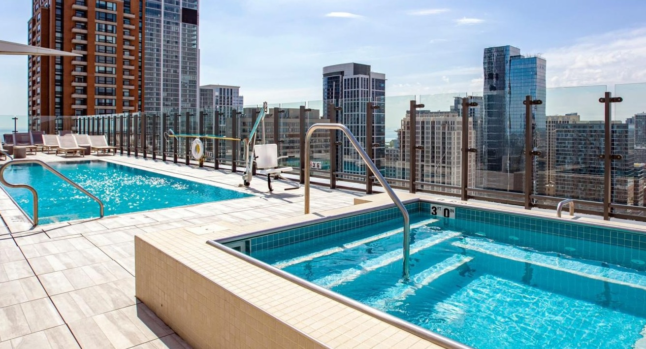 Luxurious rooftop pool and hot tub area with stunning city skyline views, perfect for relaxation at Eleven40 apartments in Chicago