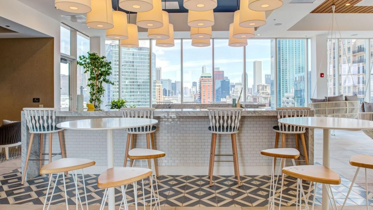 Vibrant sky lounge with a spacious bar area, high-top seating, and panoramic city views, perfect for social gatherings at Eleven40 in Chicago