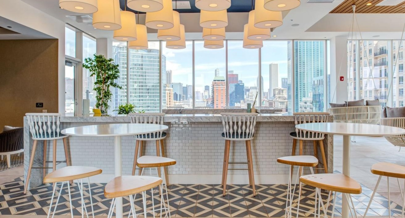Vibrant sky lounge with a spacious bar area, high-top seating, and panoramic city views, perfect for social gatherings at Eleven40 in Chicago