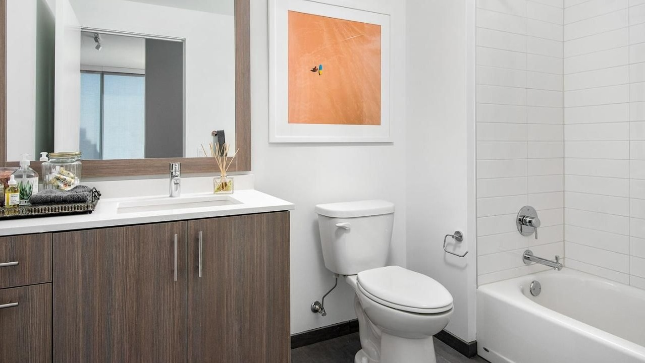 Clean and modern apartment bathroom with a wood-look vanity, shower-tub combo, and contemporary design at Eleven40 apartments in Chicago
