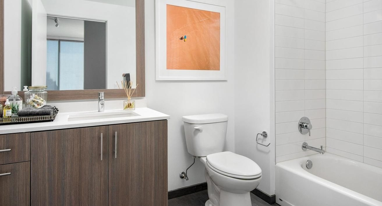 Clean and modern apartment bathroom with a wood-look vanity, shower-tub combo, and contemporary design at Eleven40 apartments in Chicago