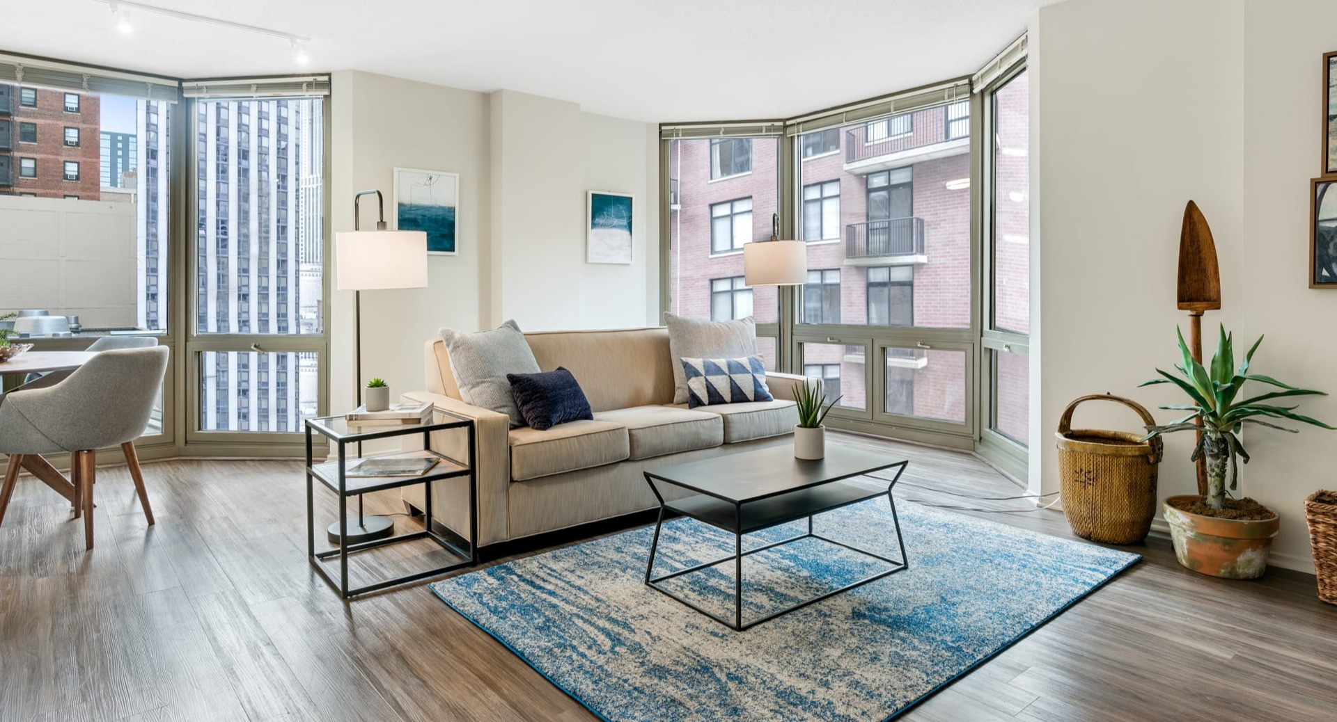 Bright living space with large bay windows, a comfortable sofa, and a vibrant blue rug at Elm Street Plaza Chicago