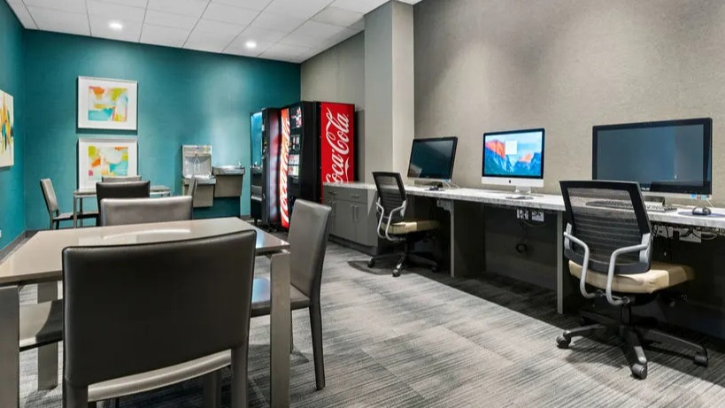 Modern business center and lounge with computer workstations and vending machines at Elm Street Plaza Chicago