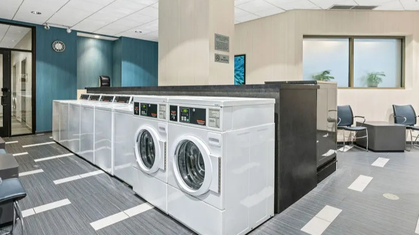 Spacious community laundry room with multiple machines and seating areas at Elm Street Plaza Chicago