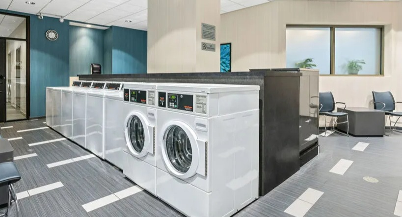 Spacious community laundry room with multiple machines and seating areas at Elm Street Plaza Chicago
