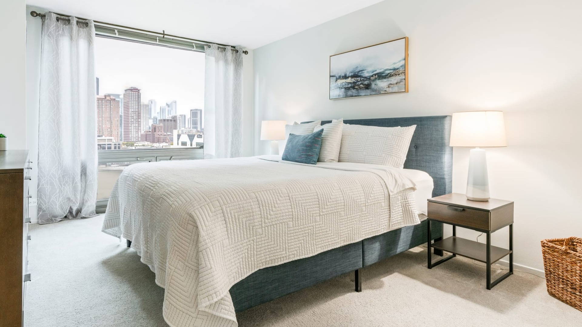 Cozy bedroom with a comfortable bed, warm lighting, and expansive city views from large windows at Elm Street Plaza Chicago