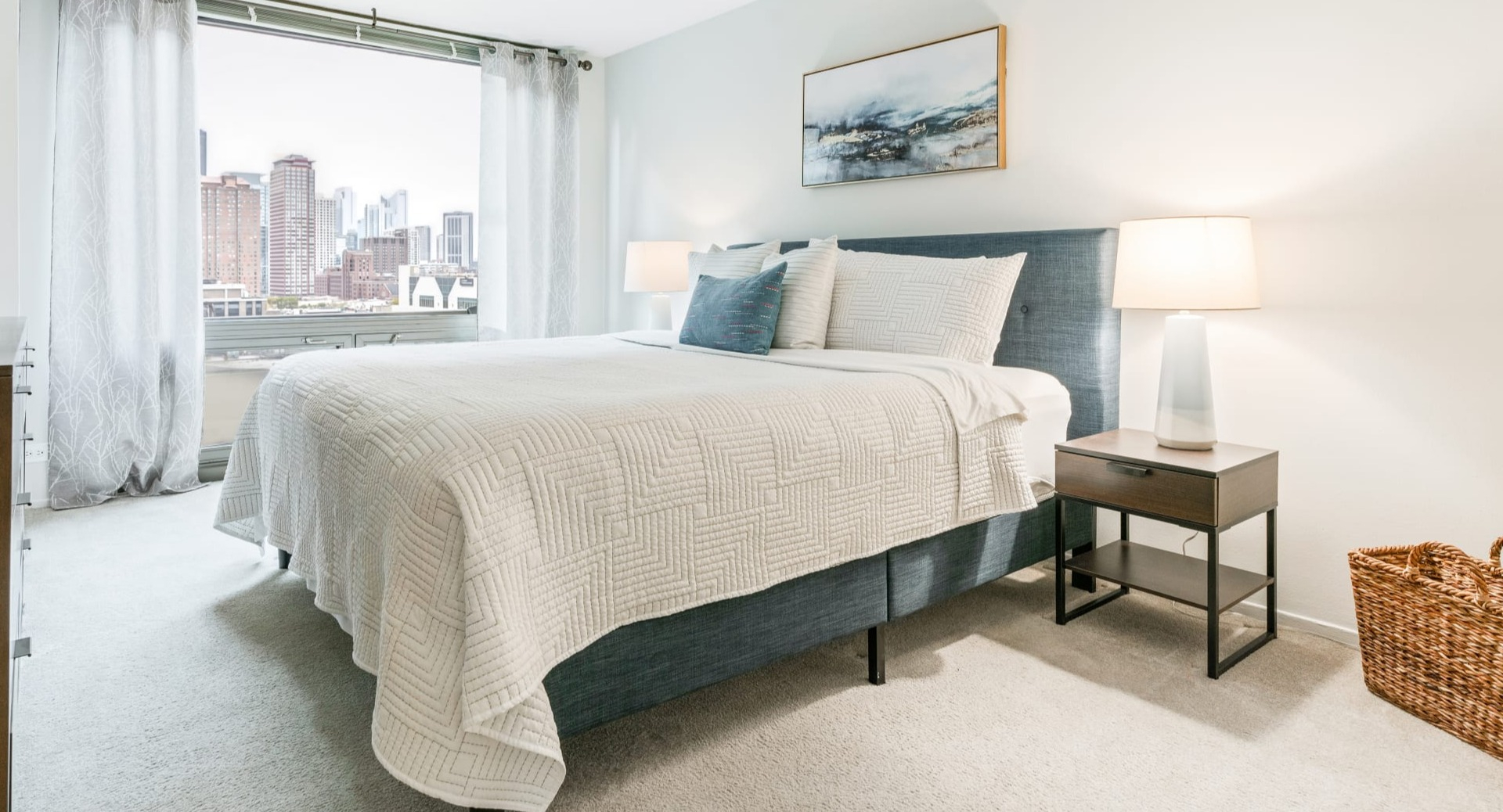Cozy bedroom with a comfortable bed, warm lighting, and expansive city views from large windows at Elm Street Plaza Chicago