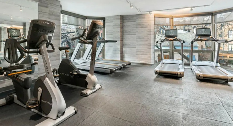 Spacious gym area with treadmills, stationary bikes, and mirrored walls at Elm Street Plaza Chicago