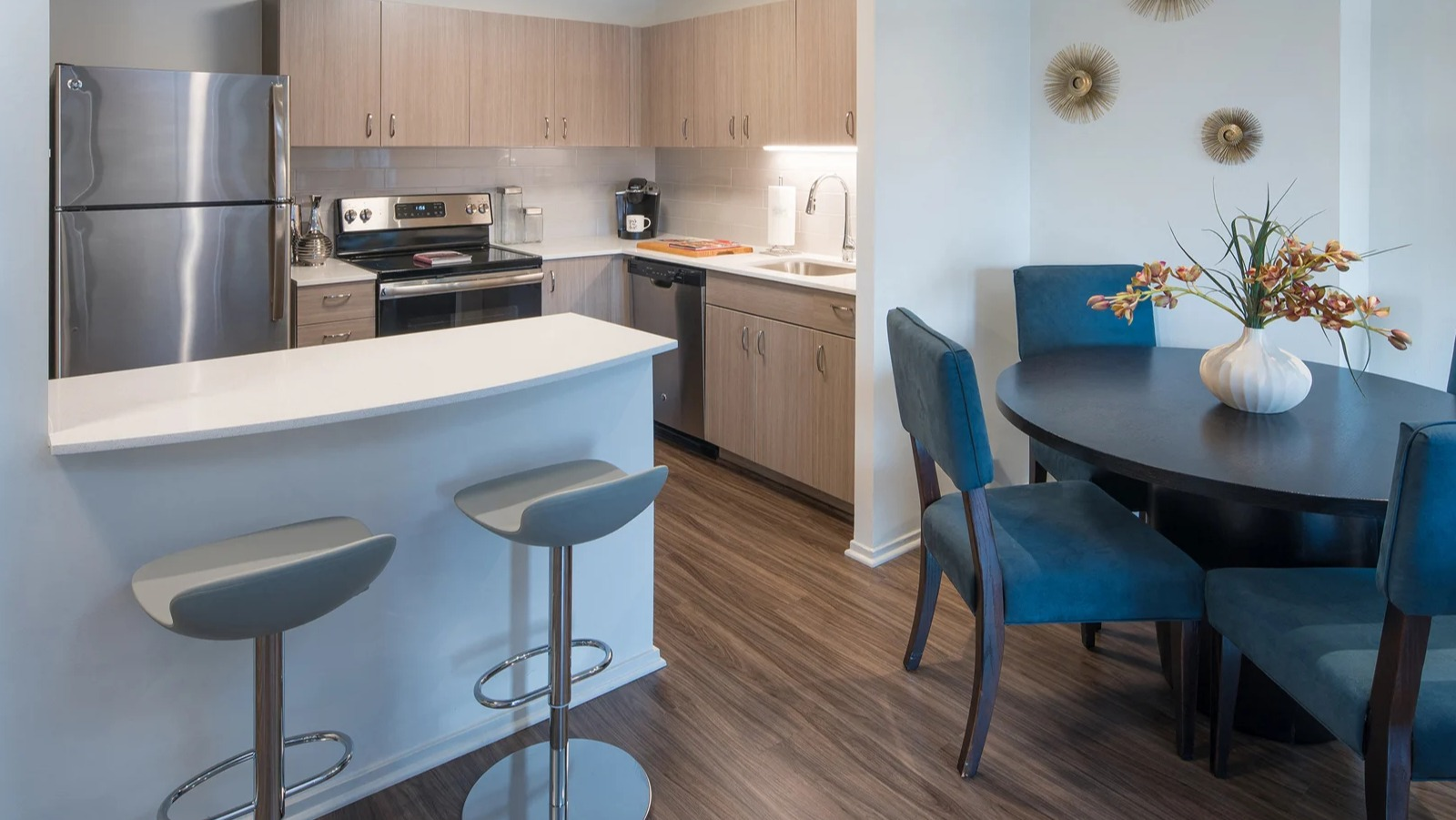 Modern kitchen and dining area with stainless steel appliances, breakfast bar, and blue dining chairs at Elm Street Plaza Chicago