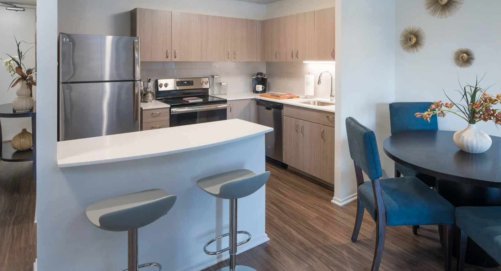 Modern kitchen and dining area with stainless steel appliances, breakfast bar, and blue dining chairs at Elm Street Plaza Chicago