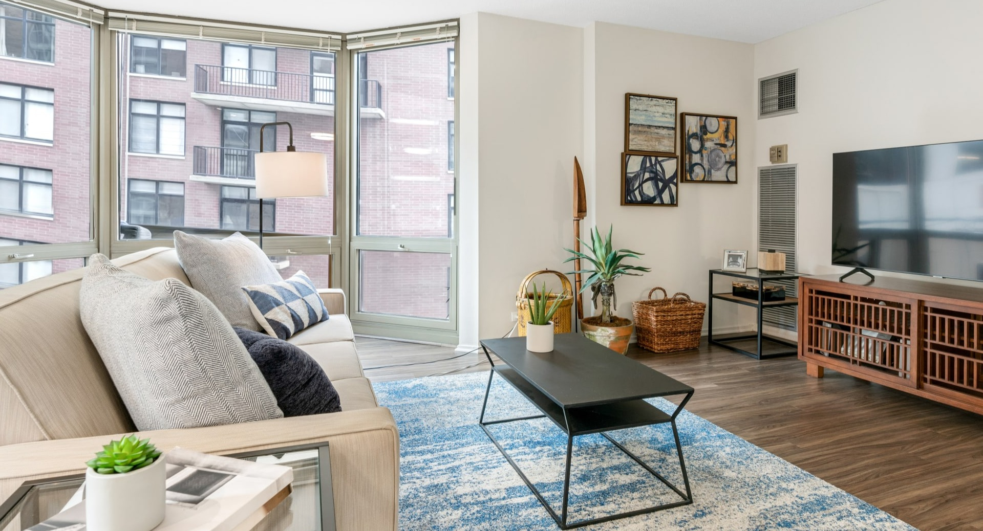 Living room designed for entertainment, featuring a television, stylish media console, and comfortable seating at Elm Street Plaza Chicago