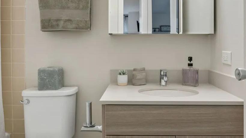 Modern bathroom with a light wood vanity, contemporary fixtures, and a shower/tub combo at Elm Street Plaza Chicago