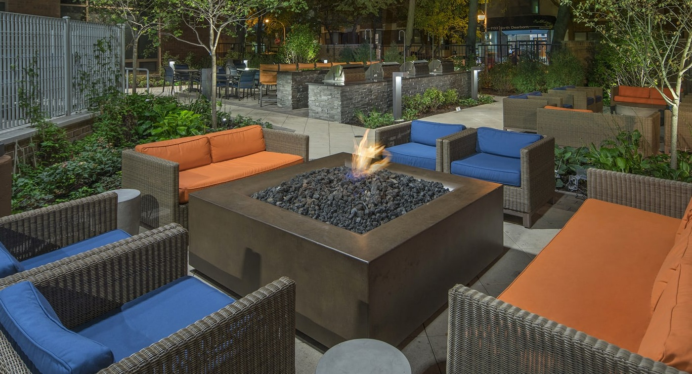 Inviting outdoor fire pit lounge area with comfortable seating and lush landscaping at Elm Street Plaza Chicago
