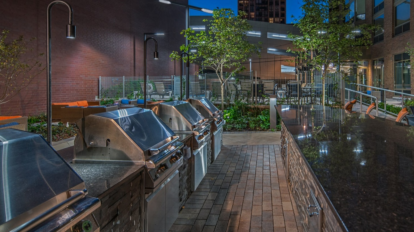 Expansive outdoor grilling station and entertaining area illuminated at night at Elm Street Plaza Chicago