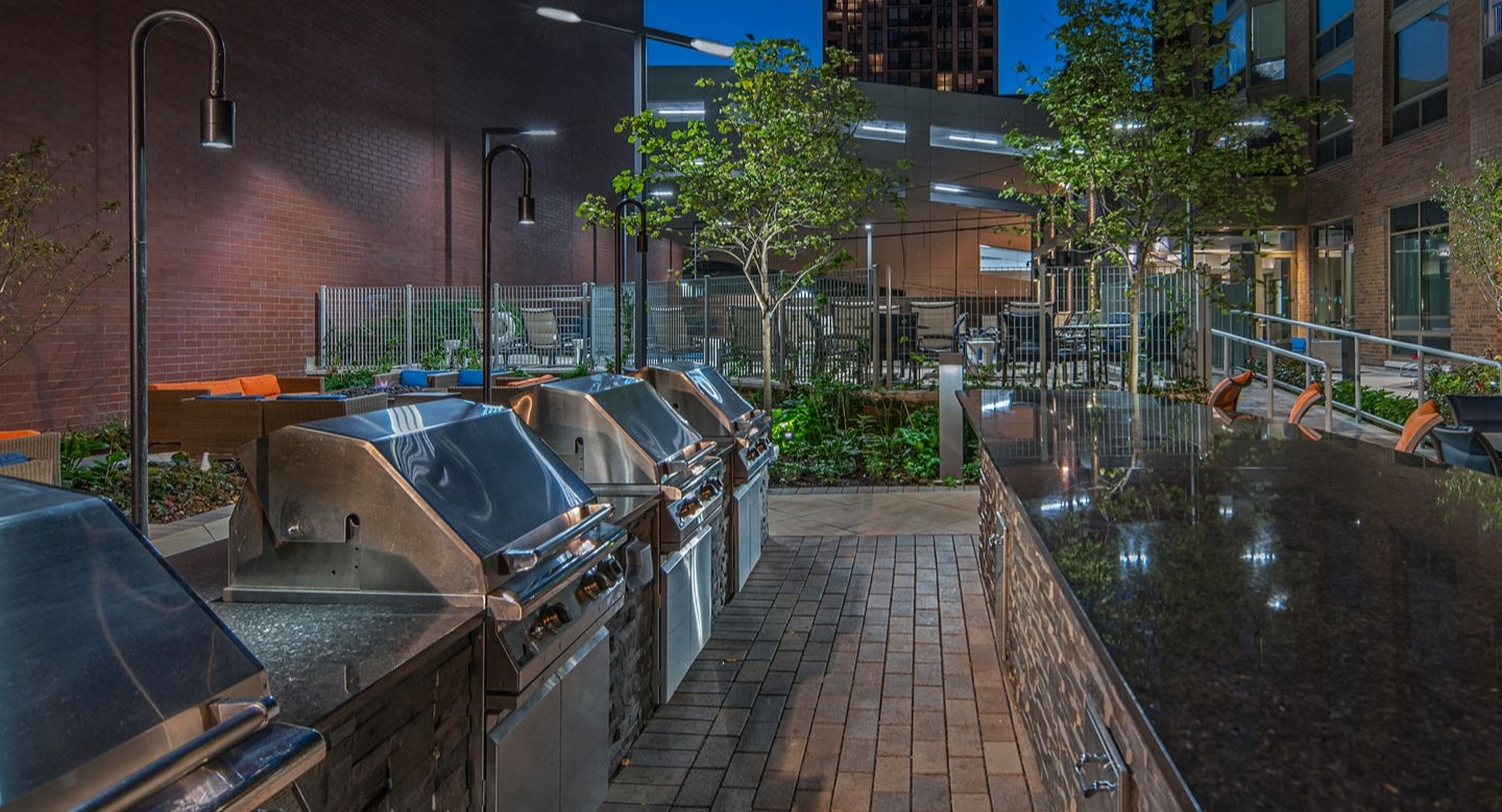 Expansive outdoor grilling station and entertaining area illuminated at night at Elm Street Plaza Chicago