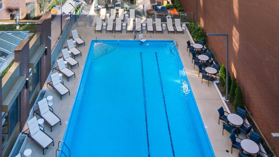 Aerial view of the outdoor swimming pool area surrounded by lounge chairs and city buildings at Elm Street Plaza Chicago