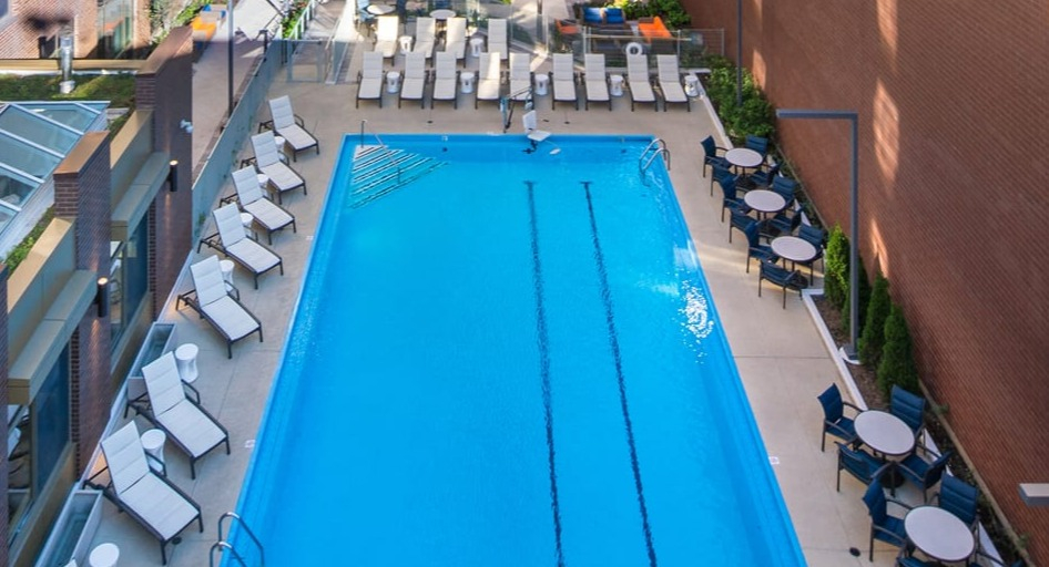Aerial view of the outdoor swimming pool area surrounded by lounge chairs and city buildings at Elm Street Plaza Chicago