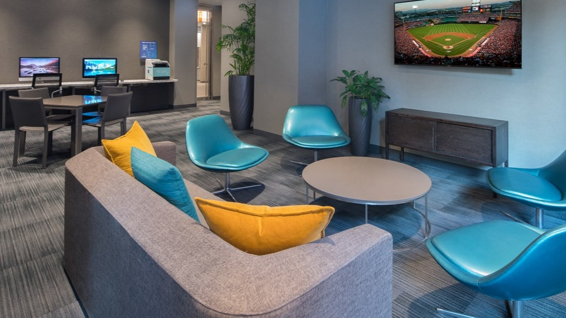 Stylish resident lounge area with computers, comfortable seating, and a large TV for entertainment at Elm Street Plaza Chicago