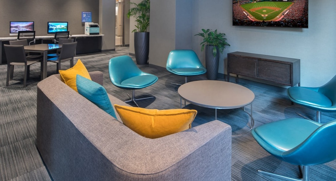 Stylish resident lounge area with computers, comfortable seating, and a large TV for entertainment at Elm Street Plaza Chicago