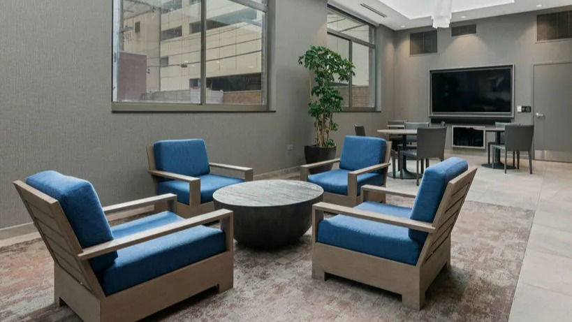 Resident lounge featuring a large screen TV, comfortable seating, and a bright, open atmosphere at Elm Street Plaza Chicago