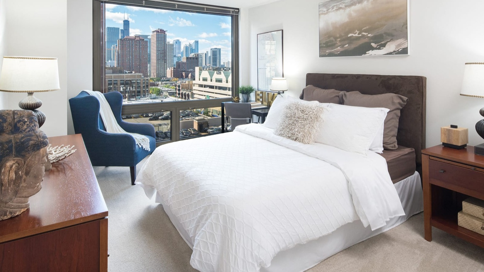 Spacious bedroom with a large bed, stylish furniture, and impressive cityscape views at Elm Street Plaza Chicago