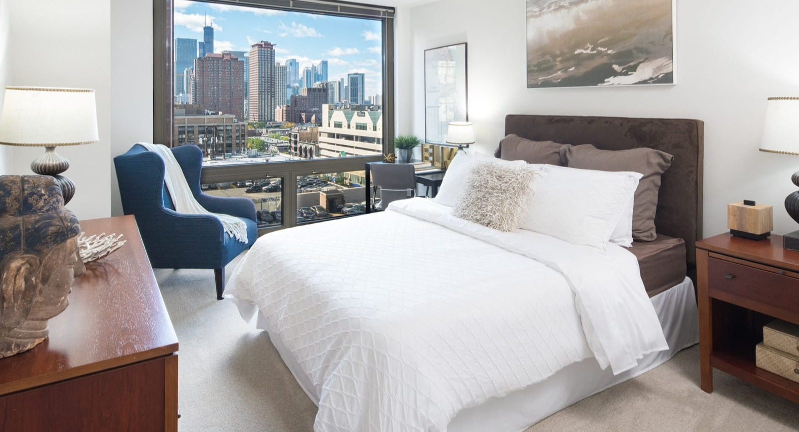 Spacious bedroom with a large bed, stylish furniture, and impressive cityscape views at Elm Street Plaza Chicago