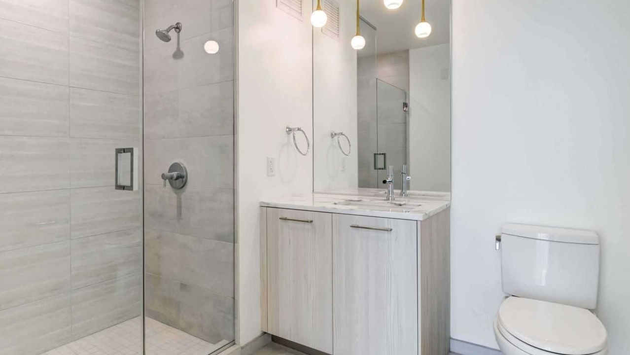 Modern bathroom with a spacious glass-enclosed shower, single vanity, and contemporary lighting at EMME Chicago in Chicago