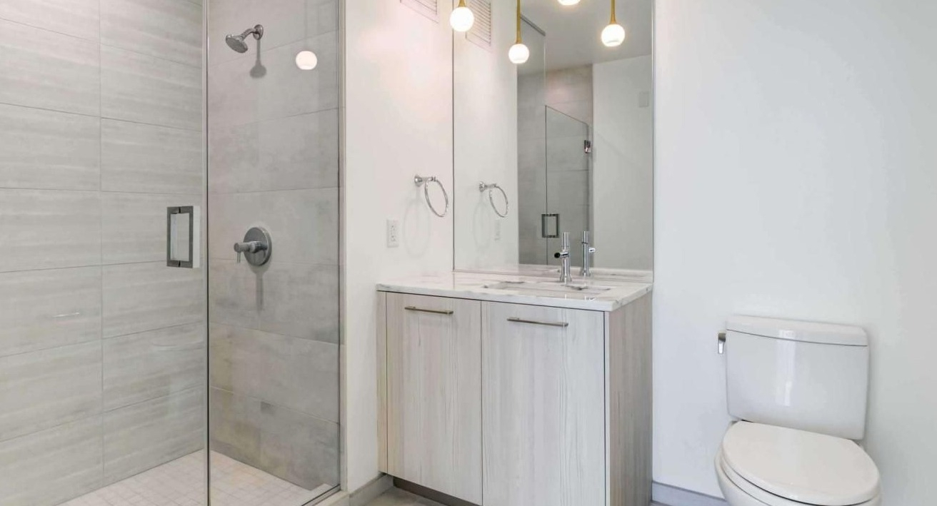 Modern bathroom with a spacious glass-enclosed shower, single vanity, and contemporary lighting at EMME Chicago in Chicago