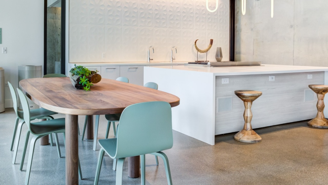 Sleek clubroom kitchen with a large island, bar stools, and a dining table, featuring contemporary design at EMME Chicago in Chicago