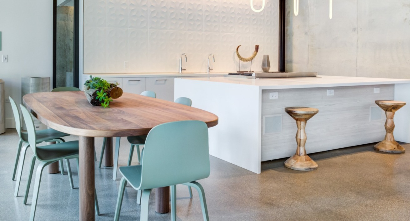 Sleek clubroom kitchen with a large island, bar stools, and a dining table, featuring contemporary design at EMME Chicago in Chicago