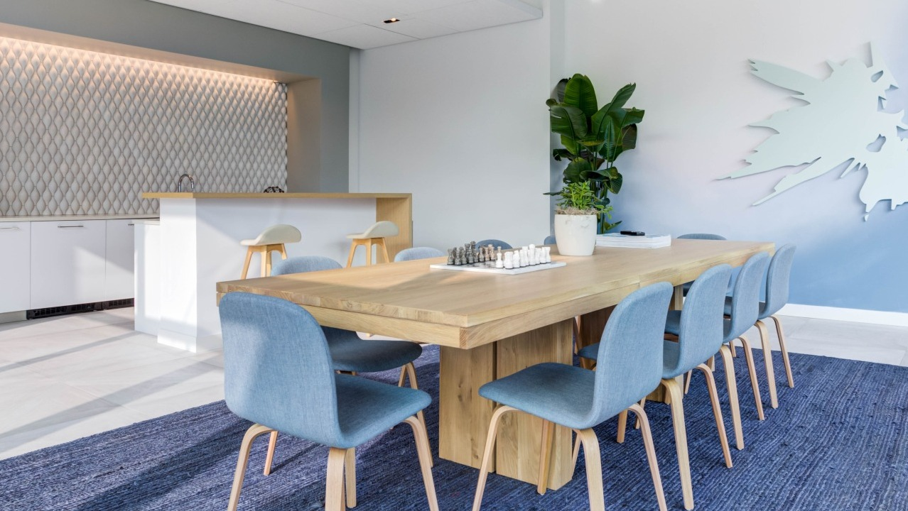 Bright community kitchen and lounge area with a long wooden table, seating, and modern kitchen facilities at EMME Chicago in Chicago