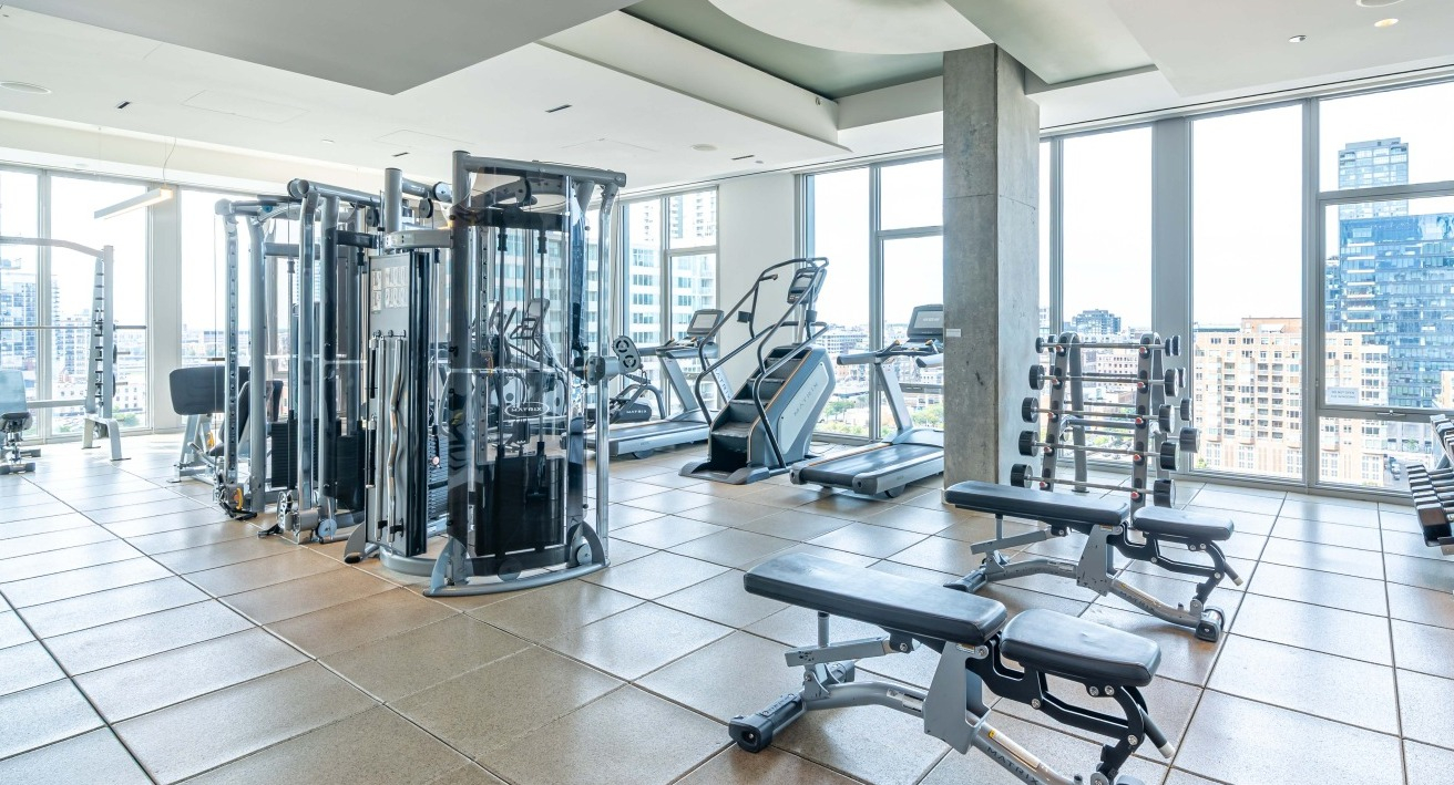 Fully equipped fitness center with a variety of strength training and cardio machines, offering city views at EMME Chicago in Chicago