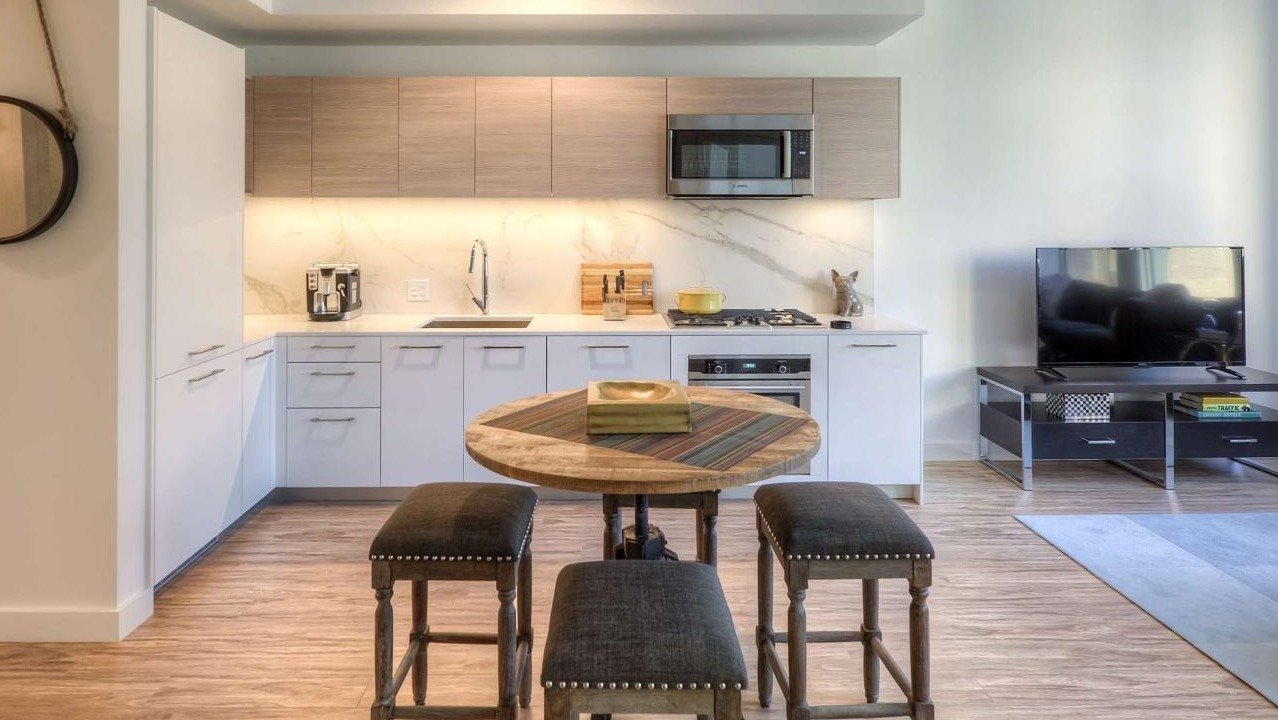 Compact and stylish kitchen with modern appliances, a circular dining table, and bar stools, integrated with the living area at EMME Chicago in Chicago