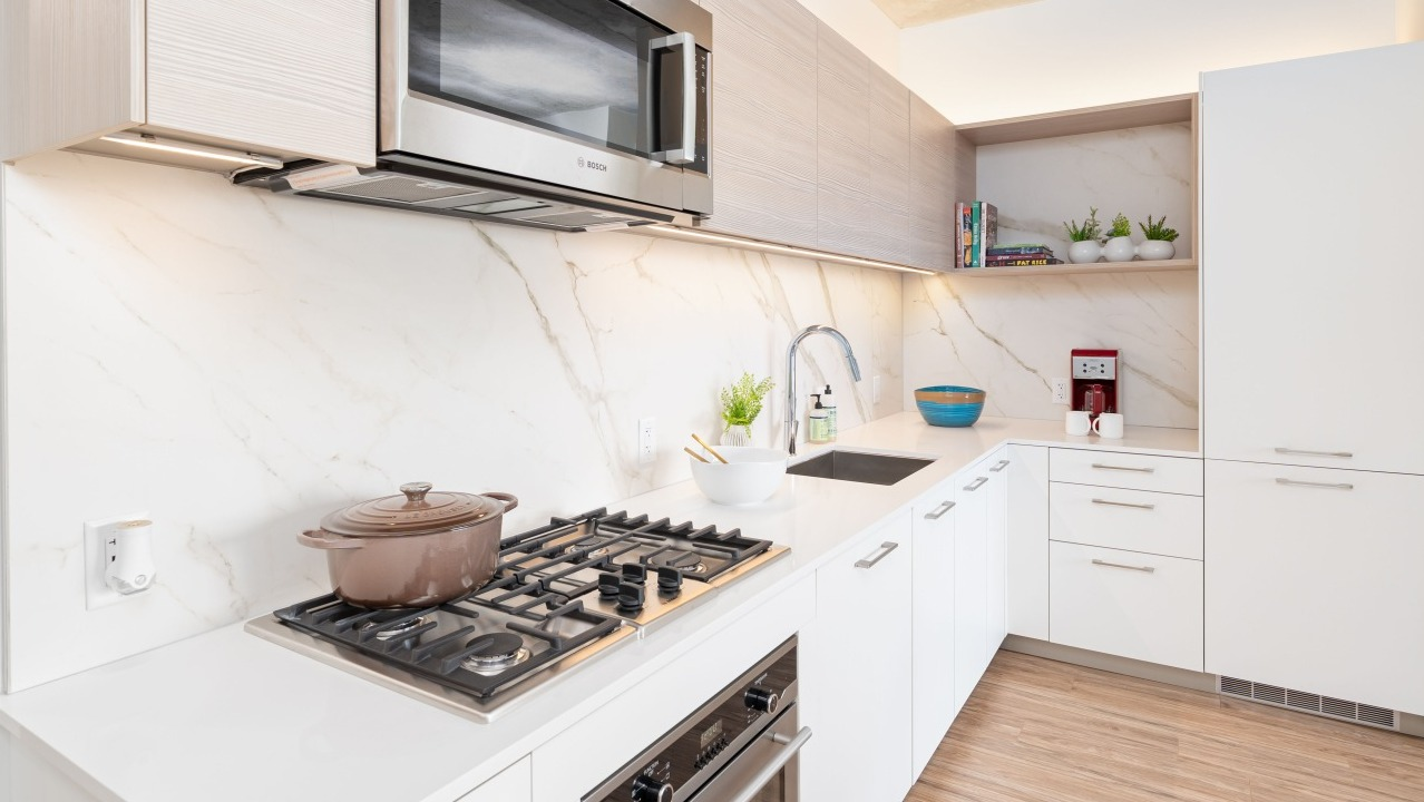 Gourmet kitchen featuring high-end stainless steel appliances, marble backsplash, ample cabinetry, and a gas range at EMME Chicago in Chicago