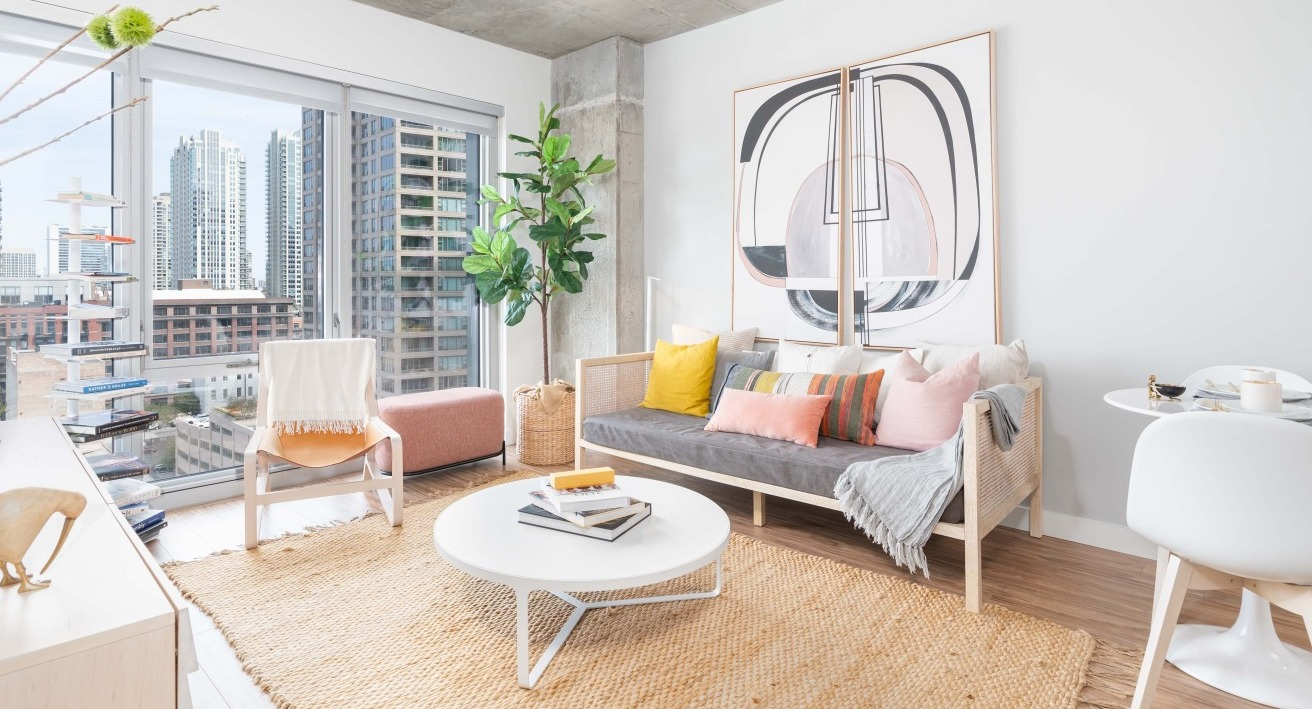 Bright and airy living room with a comfortable sofa, natural fiber rug, modern art, and expansive city views at EMME Chicago in Chicago