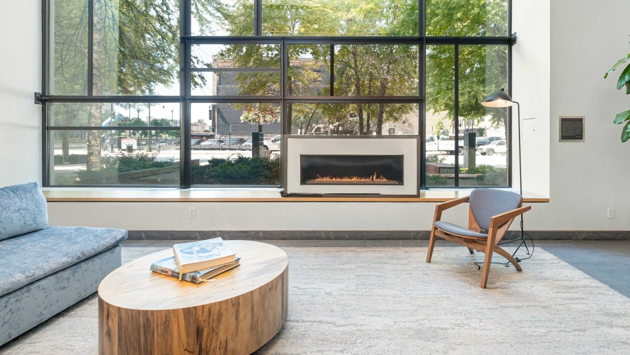 Bright and inviting lobby lounge area with a cozy fireplace, comfortable seating, and large windows at EMME Chicago in Chicago