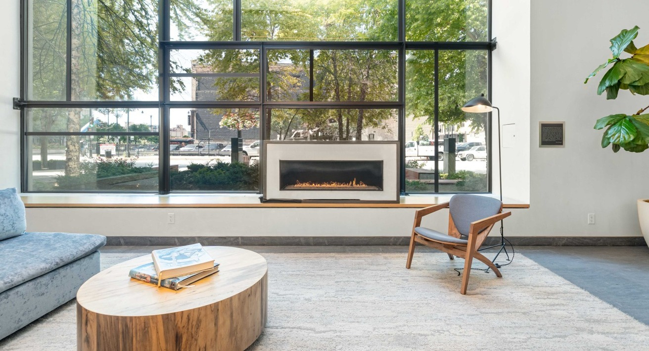 Bright and inviting lobby lounge area with a cozy fireplace, comfortable seating, and large windows at EMME Chicago in Chicago