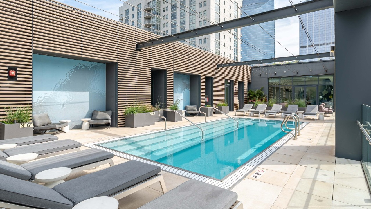 Stylish rooftop swimming pool with comfortable lounge chairs and city views, a perfect amenity at EMME Chicago in Chicago