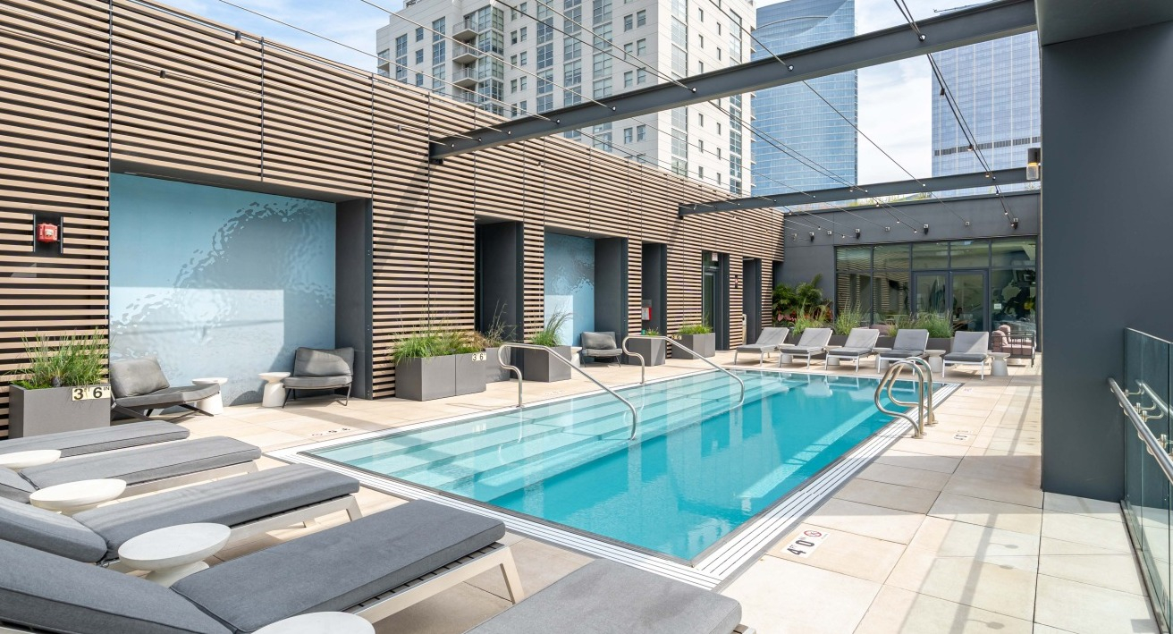 Stylish rooftop swimming pool with comfortable lounge chairs and city views, a perfect amenity at EMME Chicago in Chicago