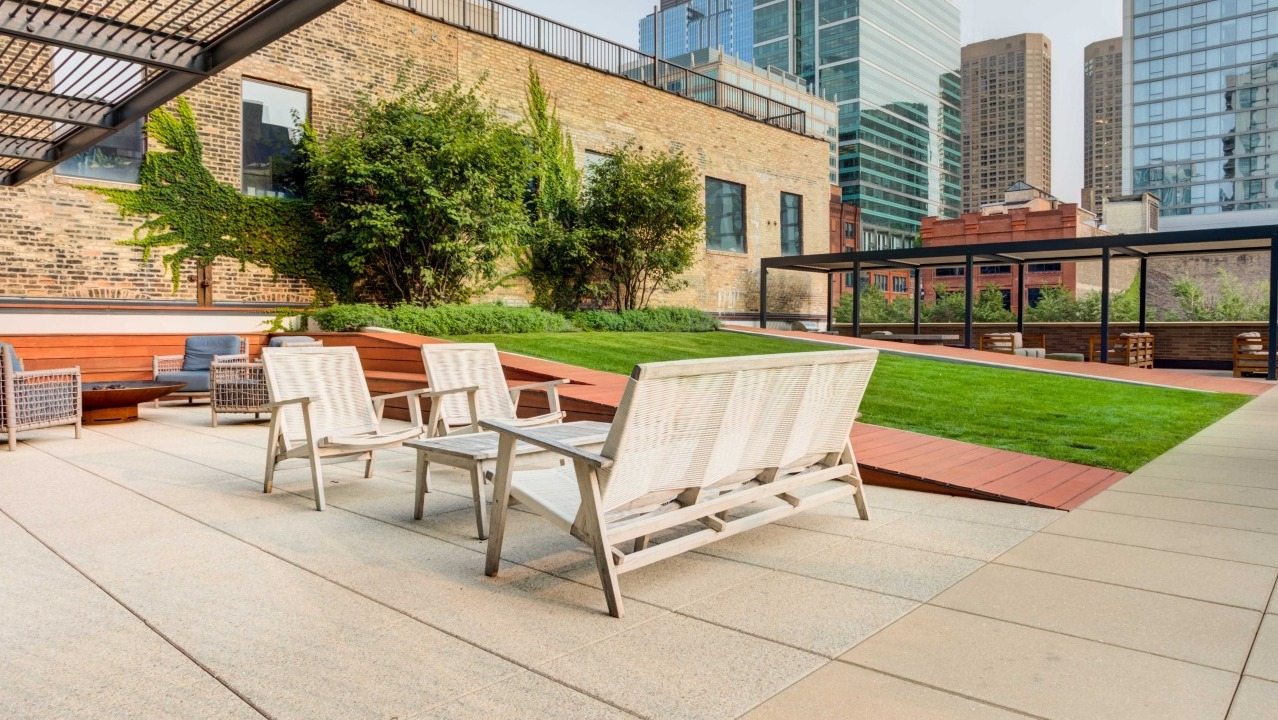 Expansive rooftop terrace with various seating areas, green spaces, and city views, perfect for relaxation at EMME Chicago in Chicago
