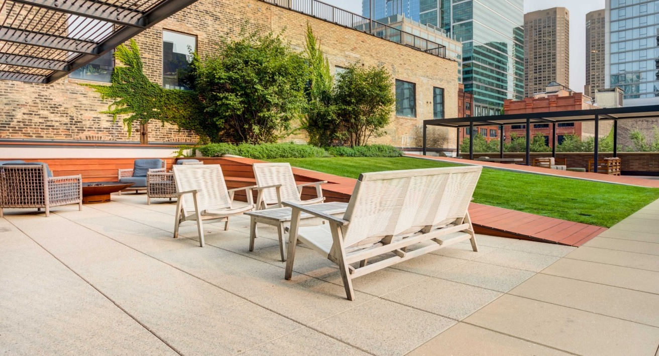 Expansive rooftop terrace with various seating areas, green spaces, and city views, perfect for relaxation at EMME Chicago in Chicago