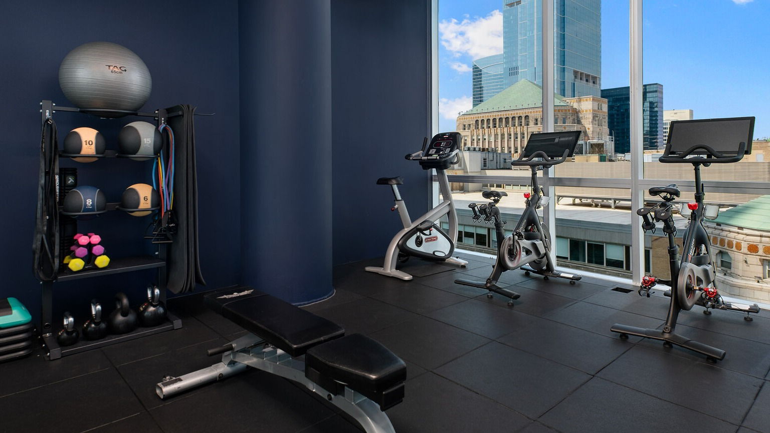 Env Chicago fitness center with exercise bikes, weights, and large windows offering inspiring city views