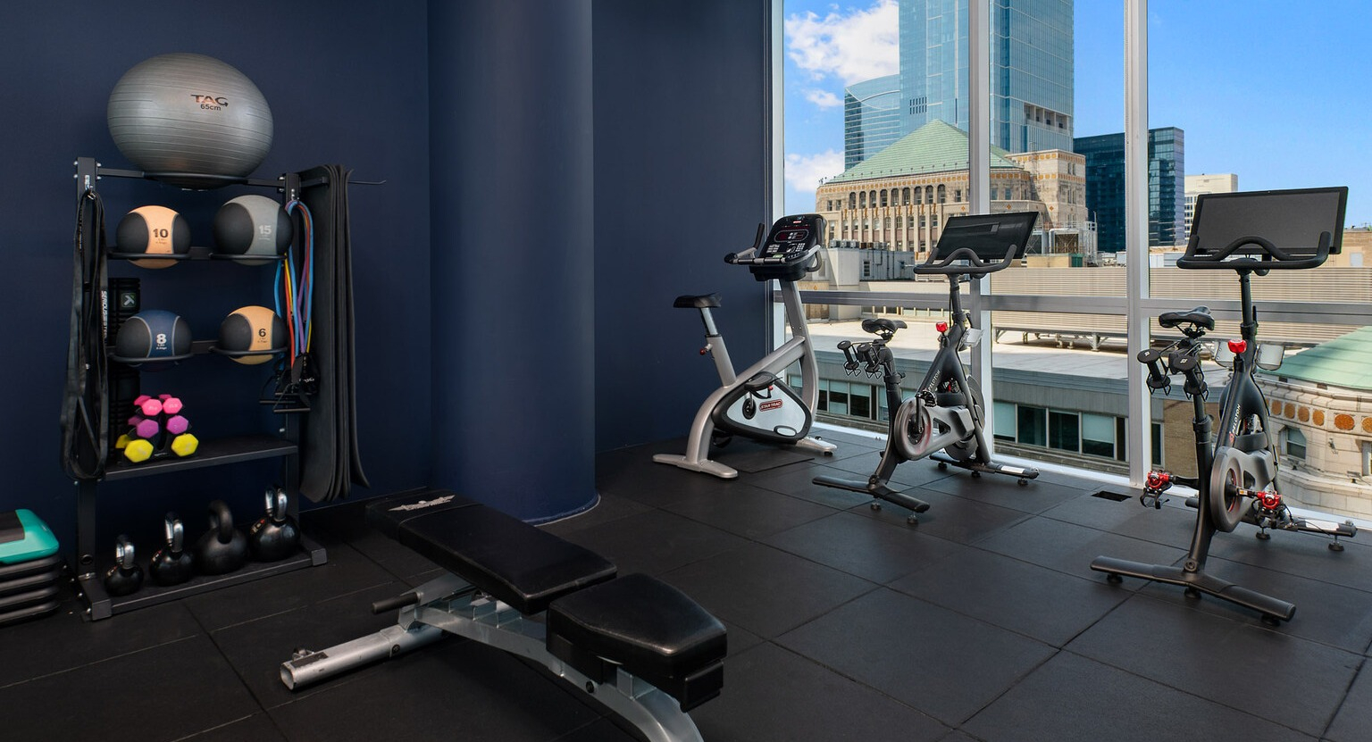 Env Chicago fitness center with exercise bikes, weights, and large windows offering inspiring city views