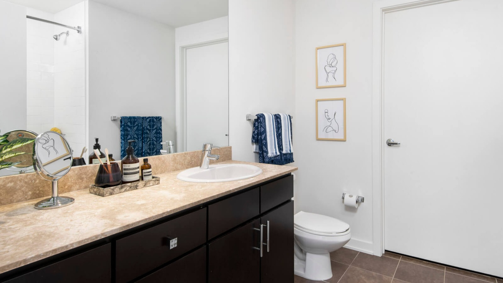 Modern bathroom at Env Chicago with a spacious vanity, large mirror, elegant fixtures, and clean white walls