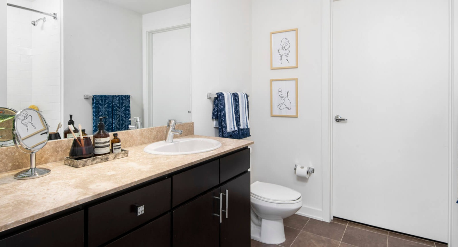 Modern bathroom at Env Chicago with a spacious vanity, large mirror, elegant fixtures, and clean white walls
