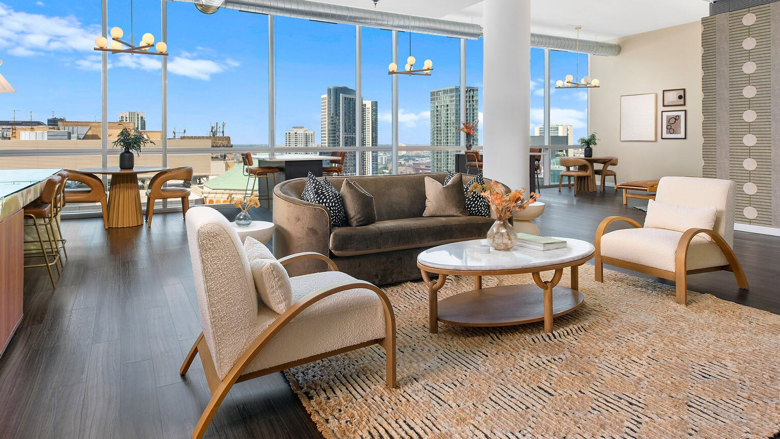 Modern resident lounge at Env Chicago with sleek gray seating, a cozy fireplace, and stunning city views for entertaining and relaxing