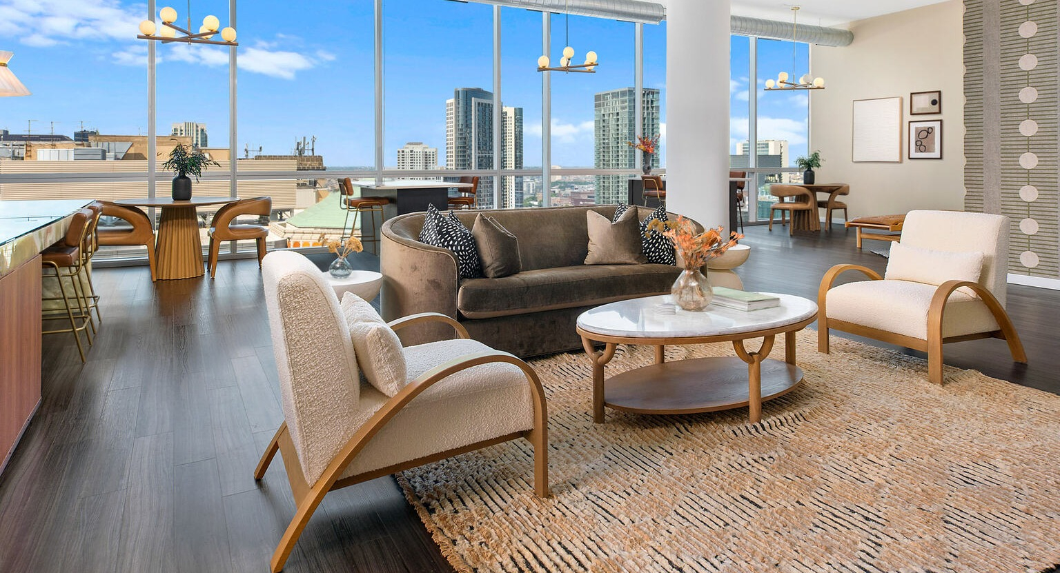 Modern resident lounge at Env Chicago with sleek gray seating, a cozy fireplace, and stunning city views for entertaining and relaxing